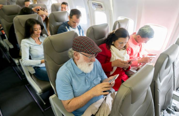 Passeggeri in aereo con il cellulare in mano