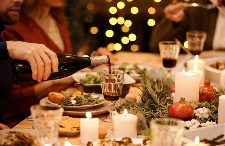 uomo versa vino in un bicchiere sulla tavola imbandita per Natale