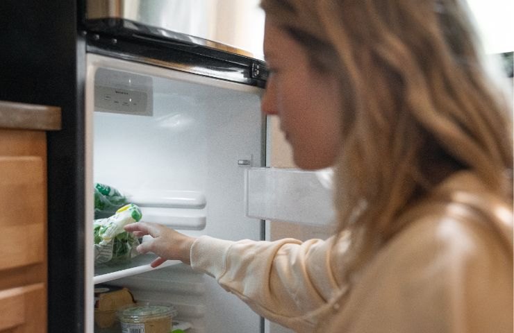 Donna prende cibo dal frigorifero 