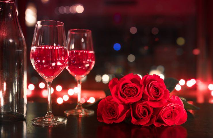 Calici di spumante e rose rosse simboli d'amore