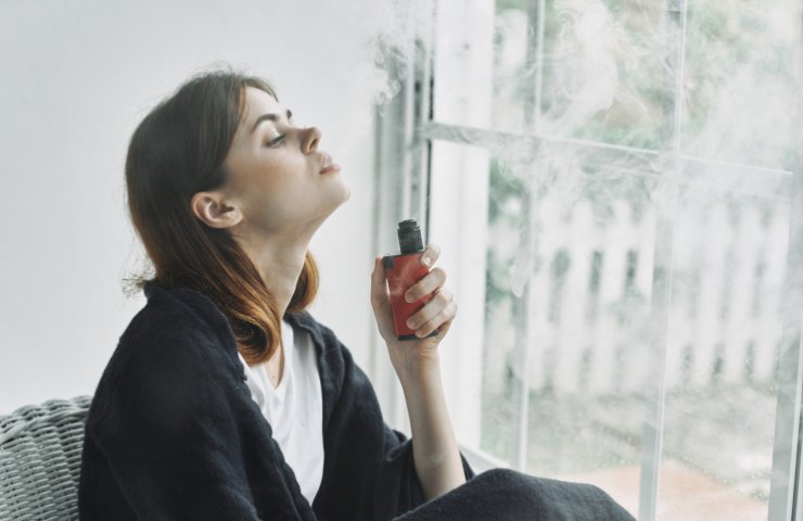 Una ragazza sbuffa fumo di sigaretta elettronica