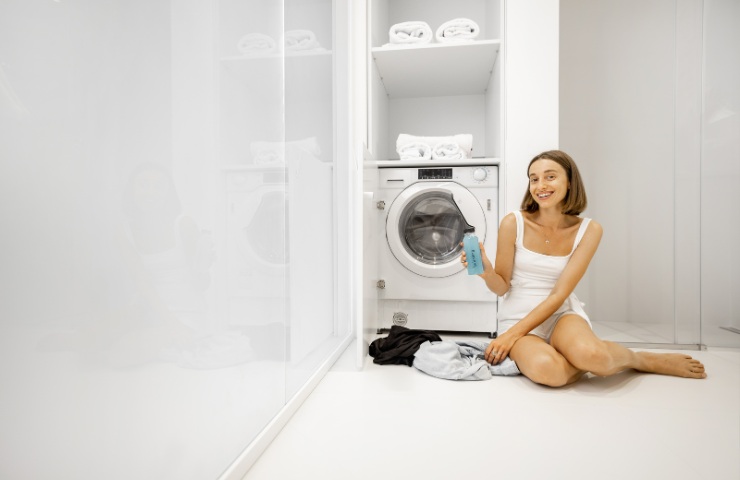 Una ragazza accanto ad una lavatrice 