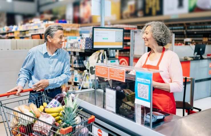 Pensionato sorridente alla cassa del supermercato